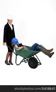 Woman pushing sleepy colleague in a wheelbarrow