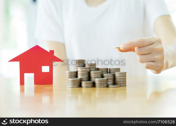 woman put coins to stack of coins and red house blackground