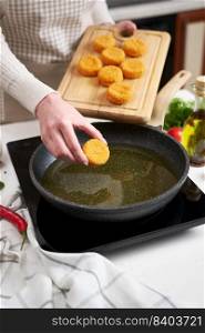 Woman puts cheese balls into frying pan with hot cooking oil.. Woman puts cheese balls into frying pan with hot cooking oil
