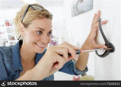 woman putting a hook on the wall