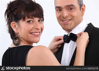 Woman putting bow tie to man