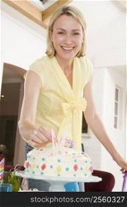Woman putting candles in cake smiling