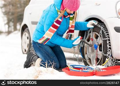 Woman putting chains on car tires snow broken winter fixing