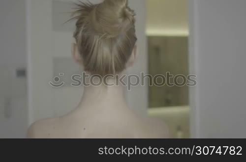 Woman putting hair in ponytail before shower