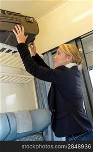 Woman putting her baggage on train grid compartment lifting commuter