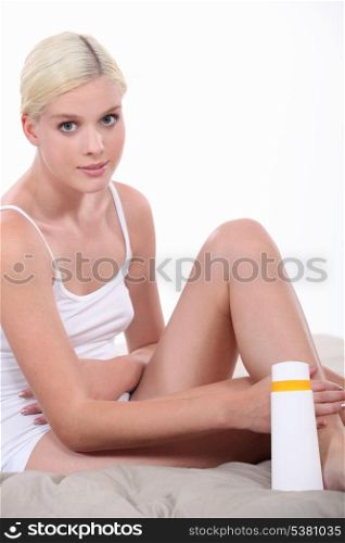 woman putting lotion on legs
