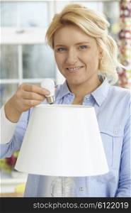 Woman Putting Low Energy LED Lightbulb Into Lamp At Home
