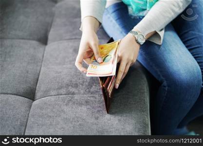 Woman putting money salary cash in the wallet taking from man husband