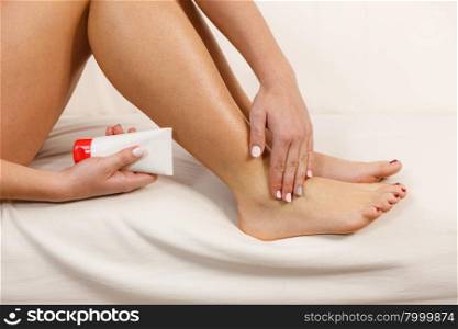 Woman putting ointment on bad ankle applying cream. Woman fit girl putting ointment cream on bad injured ankle or applying moisturizer cosmetic cream on foot. Health skin care.