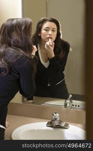 Woman putting on lipstick in restroom