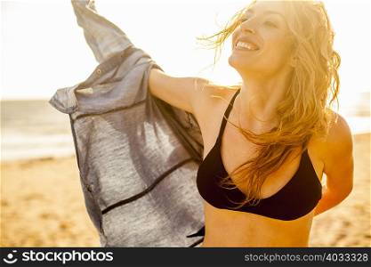 Woman putting on shirt on beach