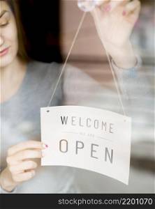 woman putting open sign window coffee shop