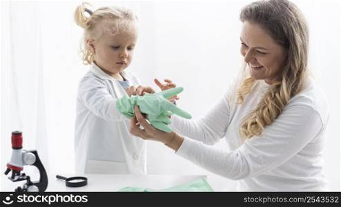 woman putting safety gloves toddler before learning about science