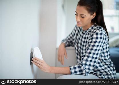 Woman Putting Smart Plug Into Power Socket At Home