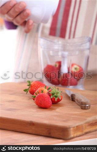 Woman putting strawberries in a blender