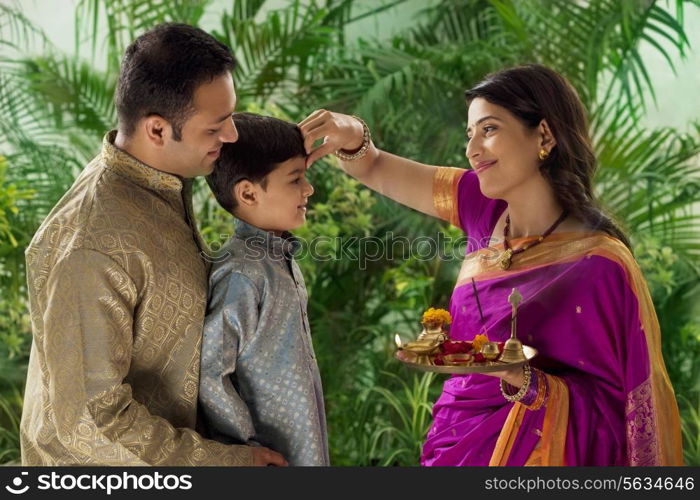 Woman putting tikka on her sons forehead