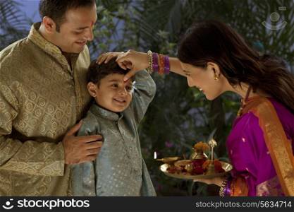 Woman putting tikka on her sons forehead