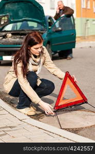 Woman putting triangle sign for car breakdown problem crash warning