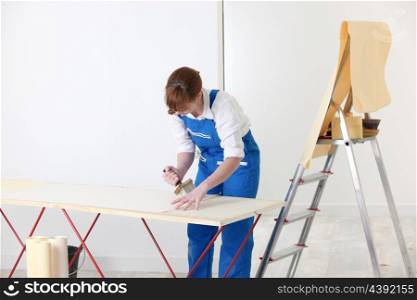 Woman putting up wallpaper