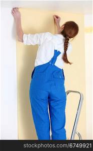 Woman putting up wallpaper
