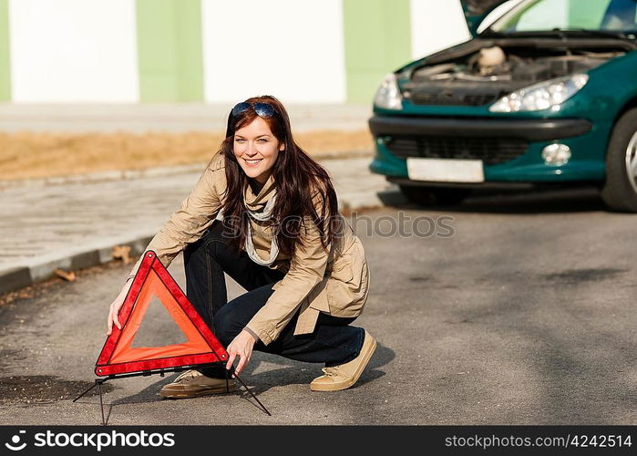 Woman putting warning triangle on the road car breakdown sign