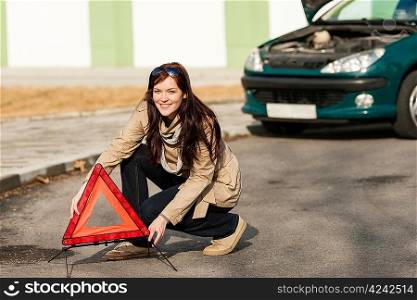 Woman putting warning triangle on the road car breakdown sign