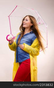 Woman rainy smiling girl wearing waterproof yellow coat standing under umbrella having fun. Meteorology, forecasting and weather season concept. Woman wearing waterproof coat under umbrella