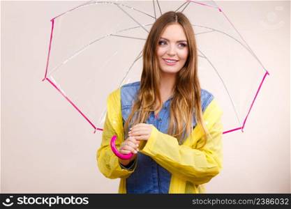 Woman rainy smiling girl wearing waterproof yellow coat standing under umbrella having fun. Meteorology, forecasting and weather season concept. Woman wearing waterproof coat under umbrella