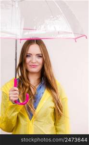 Woman rainy smiling girl wearing waterproof yellow coat standing under umbrella having fun. Meteorology, forecasting and weather season concept. Woman wearing waterproof coat under umbrella