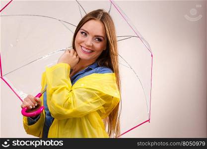 Woman rainy smiling girl wearing waterproof yellow coat standing under umbrella having fun. Meteorology, forecasting and weather season concept