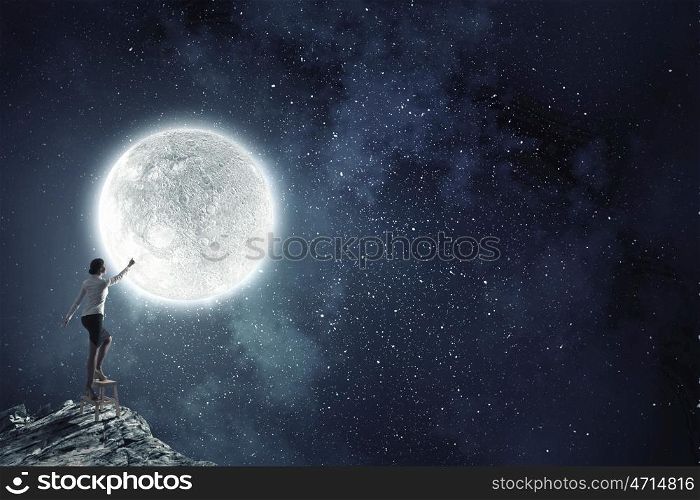 Woman reaching hand up. Businesswoman standing on chair and reaching hand to touch moon