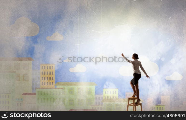 Woman reaching hand up. Businesswoman standing on chair and reaching hand to touch something