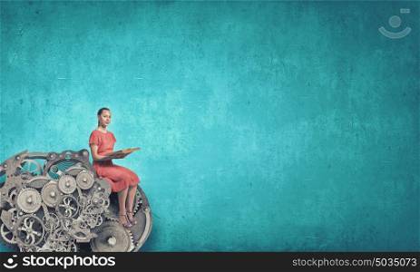 Woman read book. Young woman in red dress with book in hands sitting on gear mechanism