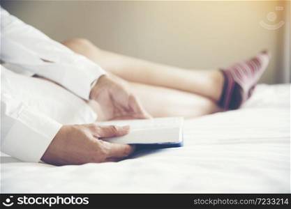 Woman reader who love reading book while sitting on bed with comfortable and relax. leisure time concept. White cozy bed with young beautiful girl, reading a book, concepts of education and learning.