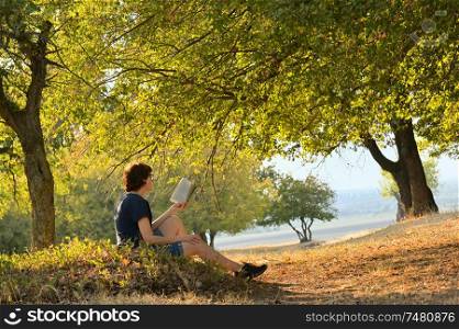 Woman reading a book in autumn forest