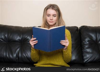 Woman reading a book on a sofa at home