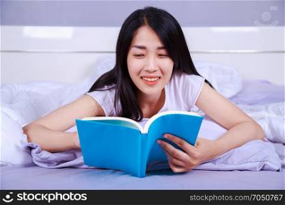 woman reading a book on bed in the bedroom at home