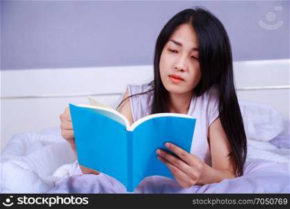 woman reading a book on bed in the bedroom at home