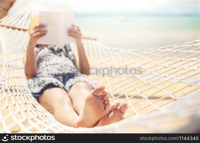 Woman reading a book on hammock beach in free time summer holiday