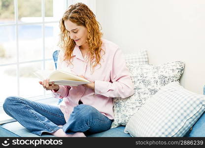 Woman reading book by window