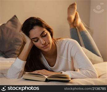 woman reading book home bed