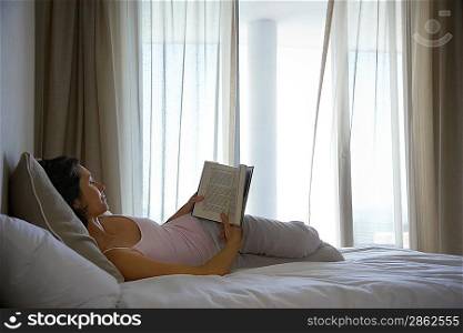 Woman Reading Book in Bed