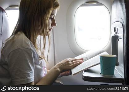 woman reading book plane