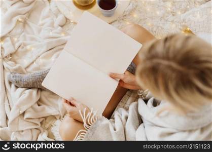 woman reading book while enjoying winter holidays