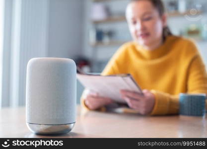 Woman Reading Magazine At Home Asking Digital Assistant Question