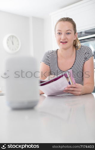 Woman Reading Magazine At Home Asking Digital Assistant Question At Home