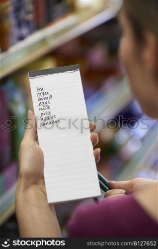 Woman Reading Shopping List In Supermarket