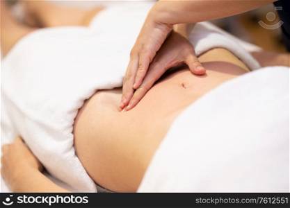Woman receiving a belly massage in a physiotherapy center. Female patient is receiving treatment by professional osteopathy therapist.. Woman receiving a belly massage in a physiotherapy center.
