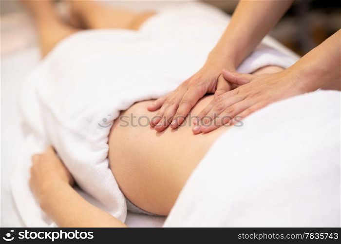 Woman receiving a belly massage in a physiotherapy center. Female patient is receiving treatment by professional osteopathy therapist.. Woman receiving a belly massage in a physiotherapy center.