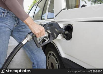 Woman refueling a car at a gas station